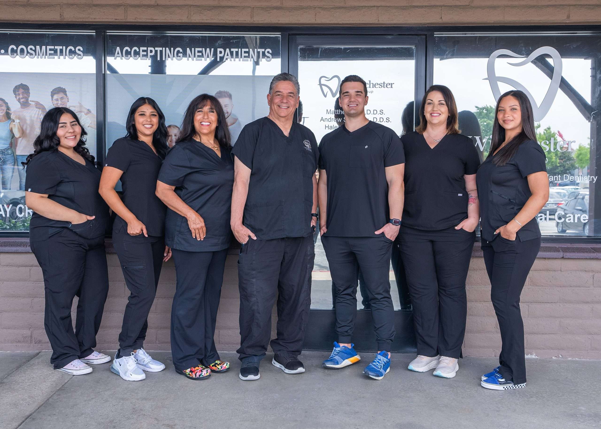 Winchester Dental Group team of seven dental professionals in black scrubs standing outside storefront