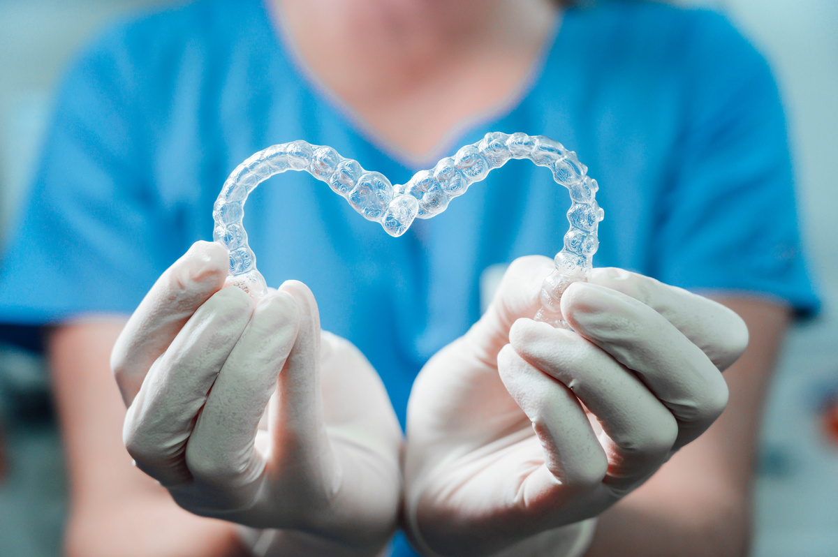 Female doctor holding two transparent heart-shaped dental aligne